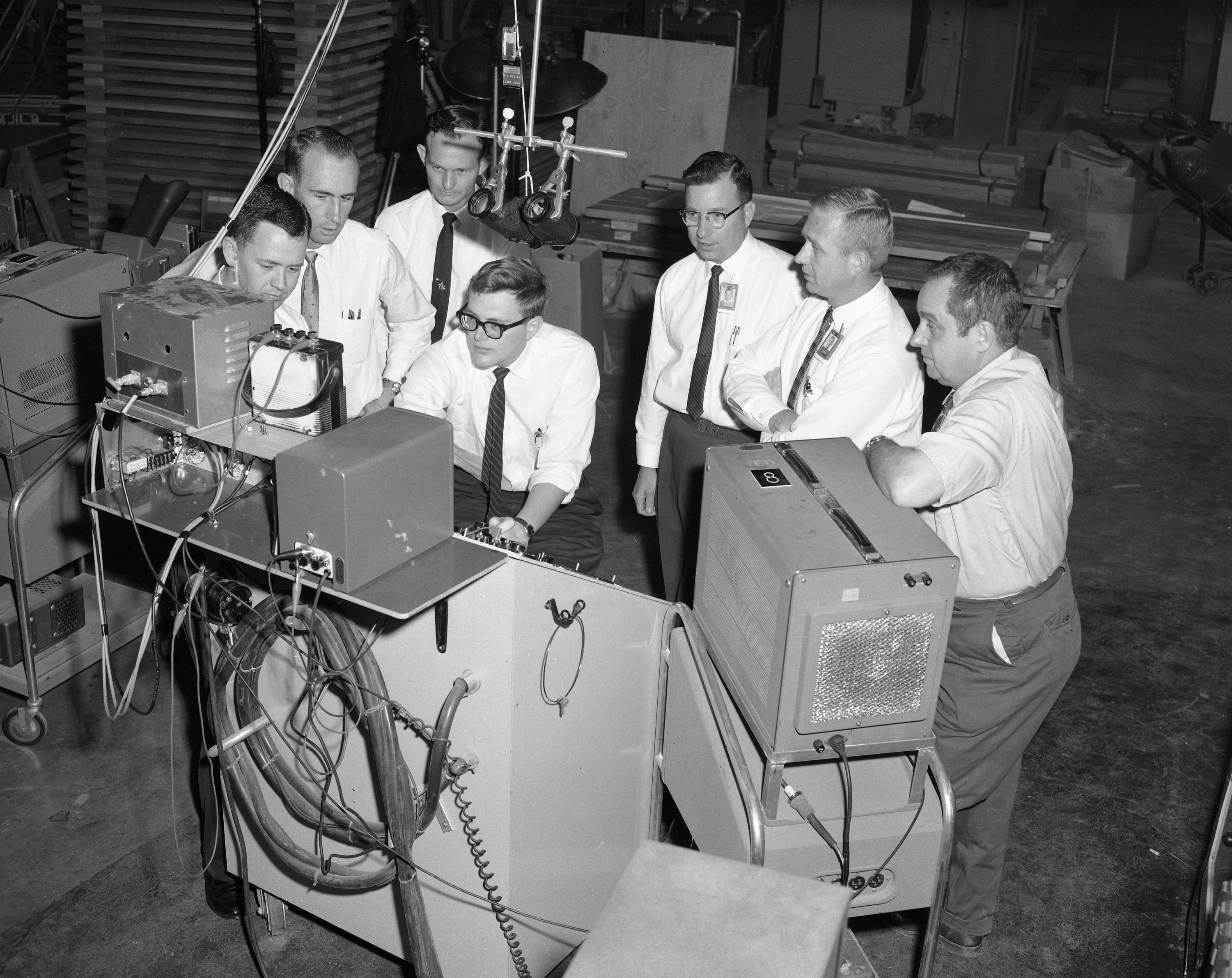 A group of Project Sherwood researchers stand around a console.
