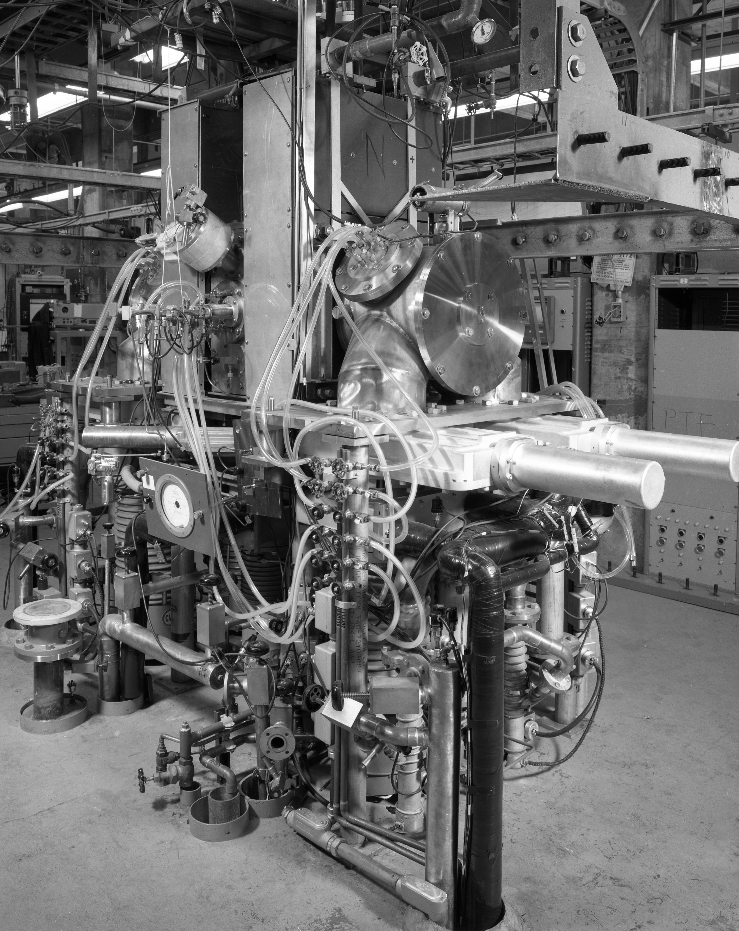 Black and white photo of the PTF, a large metal machine full of wires, tubing, and dials.