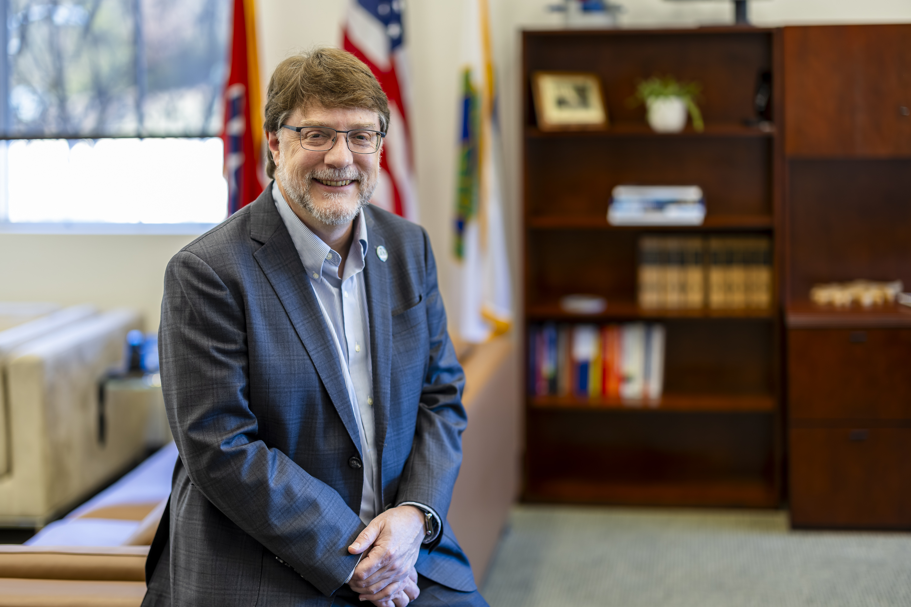 ORNL Director Stephen Streiffer sits on his desk with an American flag behind him