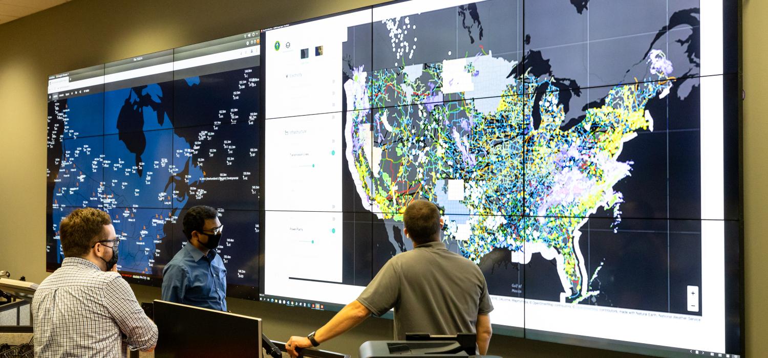 Researchers looking at large screens showing U.S. maps with data