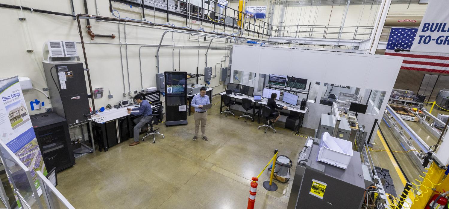 Three people sitting or standing as they conduct research in a lab containing electronic equipment and home appliances
