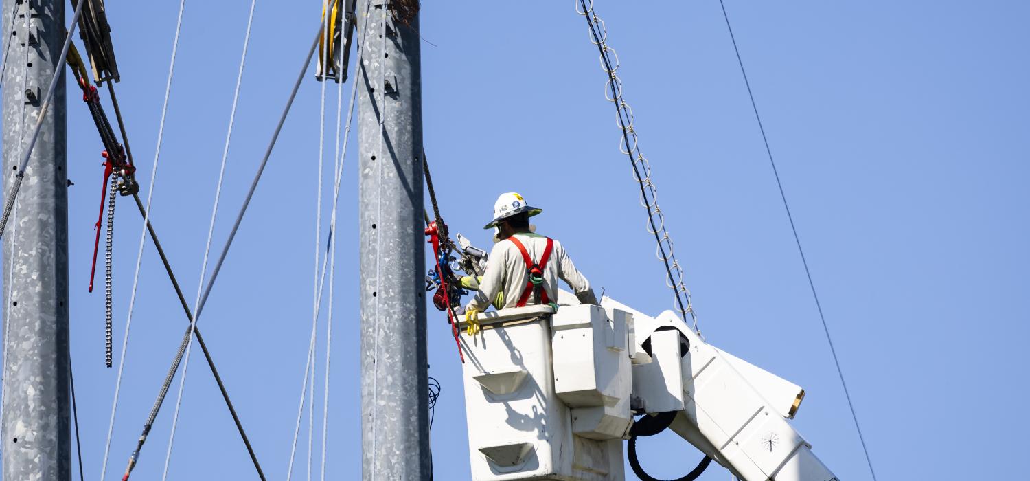 man in a bucket truck bucket working on power lines
