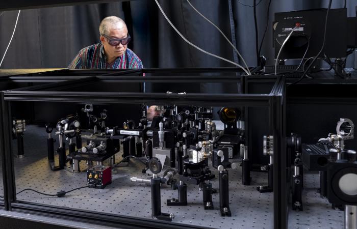 ORNL’s Yingzhong Ma examines a novel microscope that he built with collaborators. The microscope captures images using intense, ultrashort laser pulses. Credit: Carlos Jones/ORNL, U.S. Dept. of Energy
