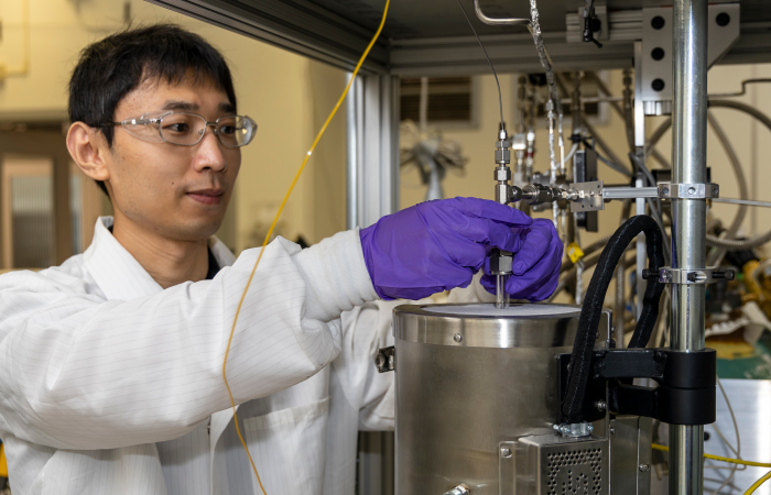 Li demonstrates how he tests the ethanol conversion catalyst material using equipment in his lab. Credit: Carlos Jones/ORNL, U.S. Dept. of Energy 
