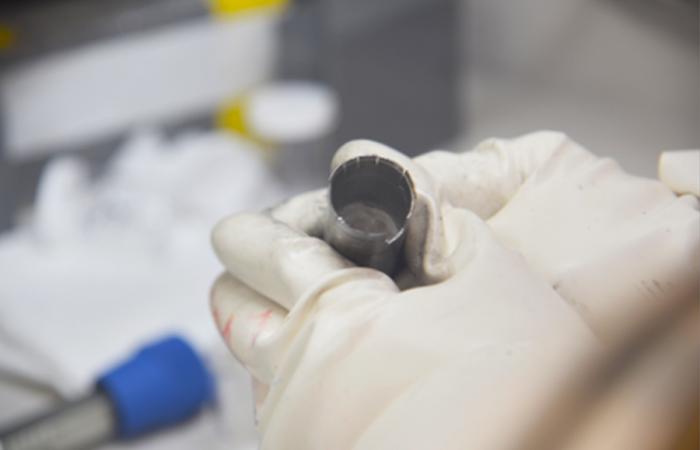 An ORNL researcher holds a capsule of molten salt. Preliminary experiments seem to indicate that irradiation can slow corrosion of metal in liquid salt. Credit: ORNL, U.S. Dept. of Energy