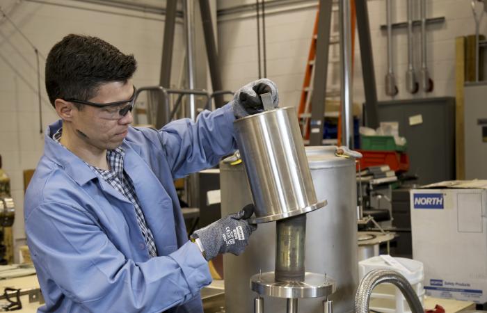 Oscar Martinez loads a special form capsule into the leak tester for a helium leak test in the packaging facility of the National Transportation Research Center. Credit: Jason Richards/ORNL, U.S. Dept. of Energy