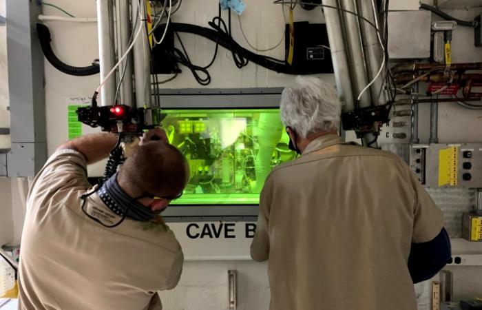 Technicians John Dyer and T. Dyer use a manipulator arm in a shielded cave in ORNL’s Radiochemical Engineering Development Center to separate concentrated Pm-147 from byproducts generated through the production of Pu-238.