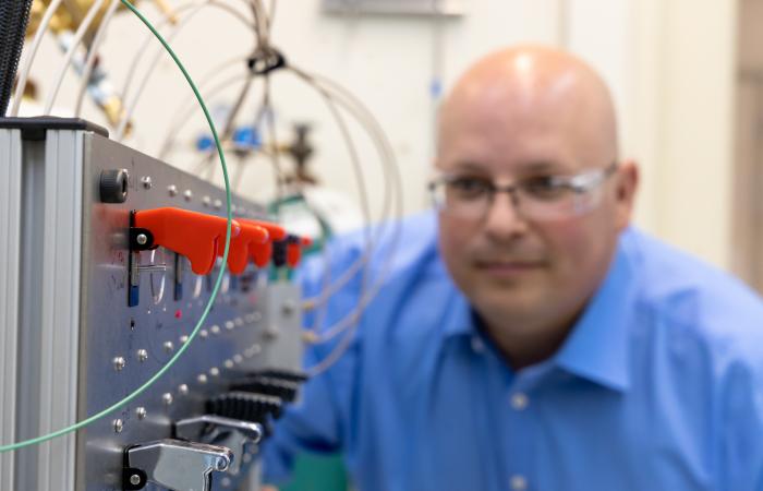 Chemist Kevin Gaddis has adapted components of a high pressure ion chromatography system  to withstand the extreme conditions of a hot cell. The pump-driven system could cut the time needed  for isotope separations by 75%. Credit: Carlos Jones/ORNL, U.S. Dept. of Energy