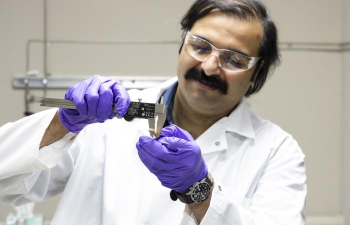 Samarthya Bhagia examines a sample of a thermoplastic composite material additively manufactured using poplar wood and polylactic acid. Credit: Carlos Jones/ORNL, U.S. Dept. of Energy