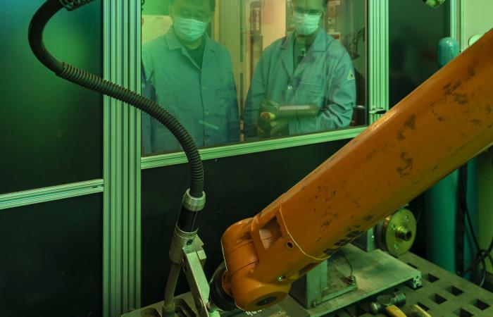 Oak Ridge National Laboratory materials scientist Zhili Feng, left, looks on as senior technician Doug Kyle operates a welding robot inside a robotic welding cell. Credit: Carlos Jones/ORNL, U.S. Dept. of Energy