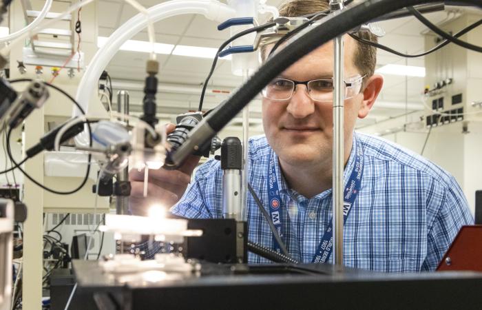 Jack Cahill of ORNL’s Biosciences Division is developing new techniques to view and measure the previously unseen to better understand important chemical processes at play in plant-microbe interactions and in human health. In this photo, Cahill is positioning a rhizosphere-on-a-chip platform for imaging by mass spectrometry. Credit: Carlos Jones/ORNL, U.S. Dept of Energy