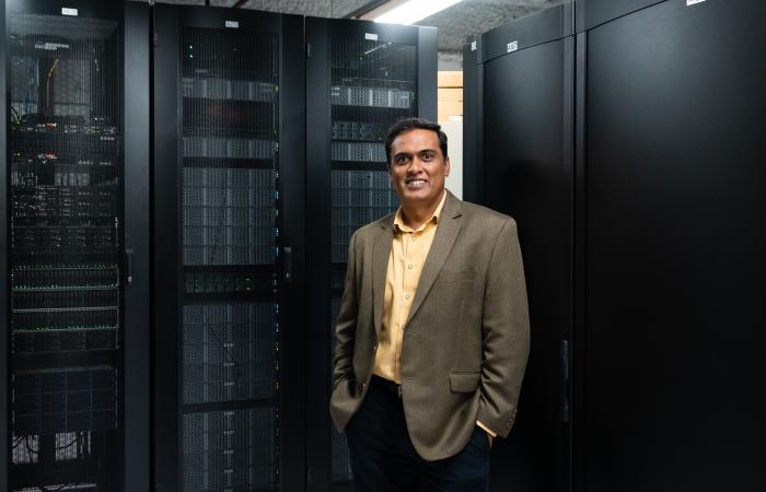 ARM Data Center Researcher Giri Prakash stands next to the latest ARM computer cluster at ORNL
