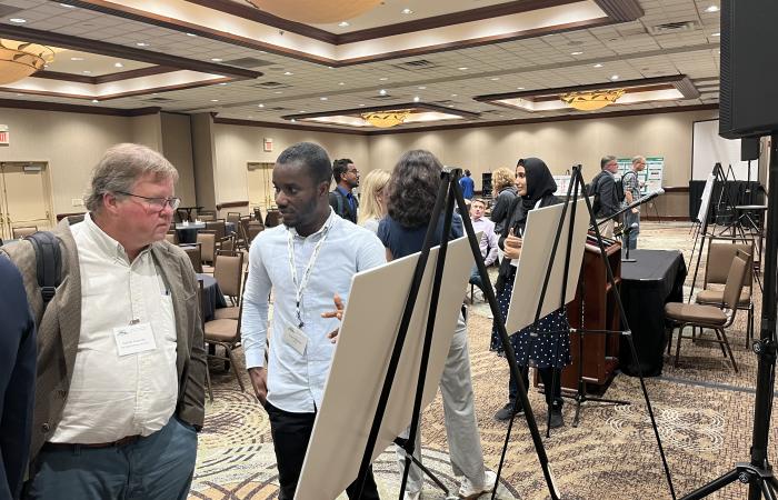 Garrett Granroth (left), an instrument scientist on the ARCS direct geometry spectrometer at the Spallation Neutron Source, listens to Evans Nyanney of the University of Texas Rio Grande Valley during the SMC poster session. The poster by Nyanney's team focused on neutron scattering of water.