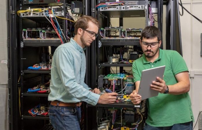 Ben Ollis, left, and Phil Irminger of Oak Ridge National Laboratory’s Power and Energy Systems Group test components on the SI-GRID platform in a safe, low-voltage setting. Credit: Carlos Jones/Oak Ridge National Laboratory, U.S. Dept. of Energy