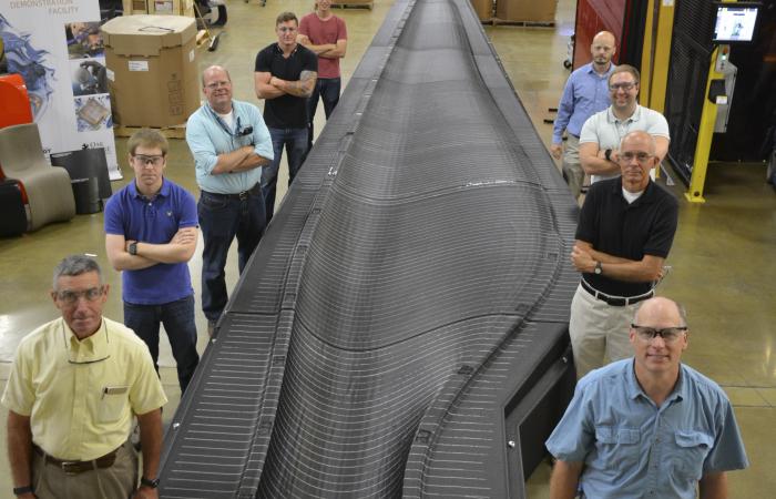 Researchers give perspective to the size of the assembled wind blade mold at DOE’s Manufacturing Demonstration Facility at ORNL. Left side, front to back: Peter Lloyd, Alex Roschli, Lonnie Love, Matt Sallas, John Lindahl. Right side, F-B: David Nuttall, R