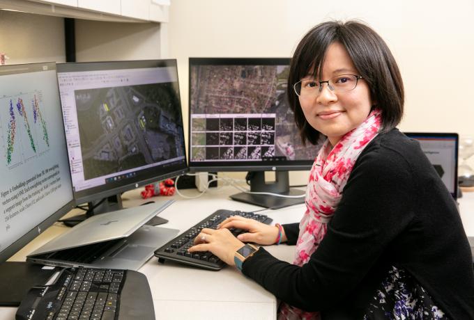 A woman works at her desk with multiple computer monitors.