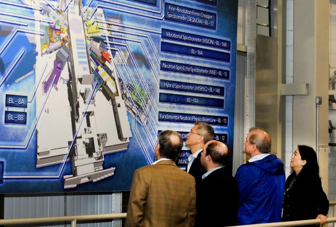 People standing in front of large map of the Spallation Neutron Source
