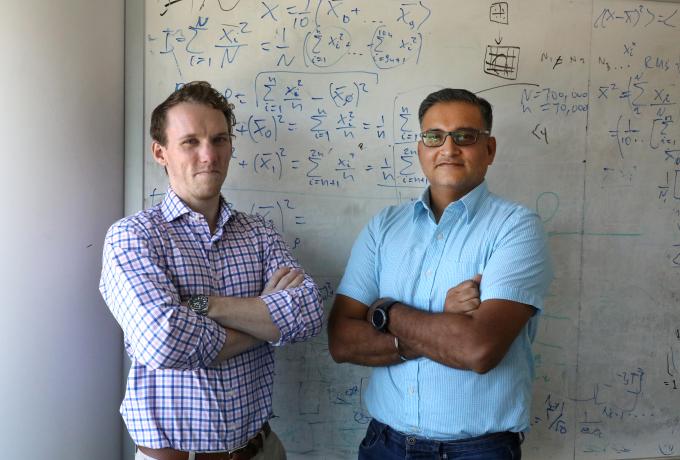Two men standing in front of white board