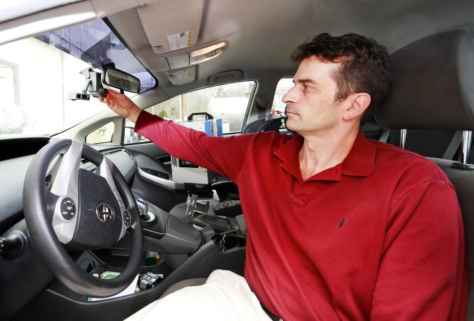 A man adjusts the rear view mirror in a Toyota Prius