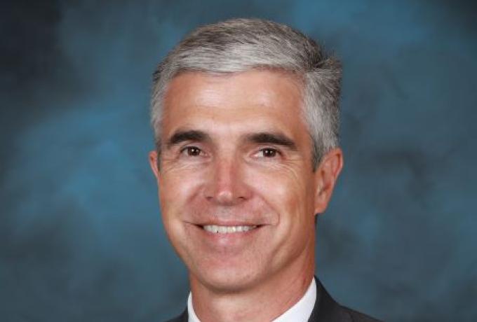 Professional portrait of a smiling male with grey hair