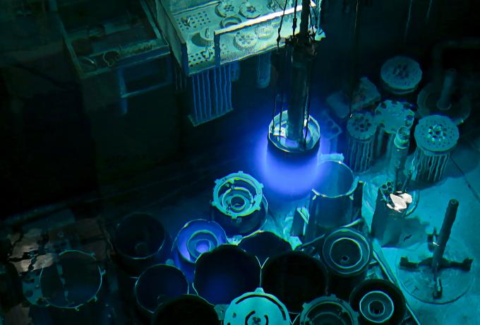 A High Flux Isotope Reactor, HFIR, outer fuel element is being moved to a storage position after an operating fuel cycle. The blue glow, known as Cherenkov Radiation, is visible light resulting from the energy released from charged particles, such as an electrons, traveling through the water at a speed that is faster than the speed of light in water.