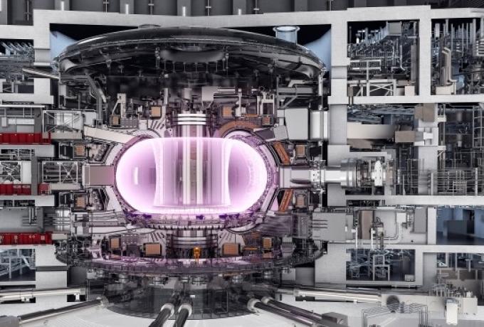 A detailed cross-sectional rendering of a fusion reactor, showing the internal structure and components of the facility. At the center, a glowing pink plasma is confined within a tokamak chamber.