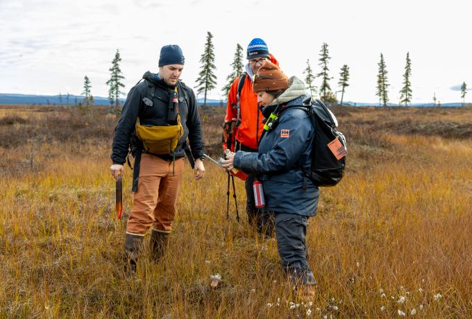 three researchers in winter gear taking samples on the Alaskan tundra