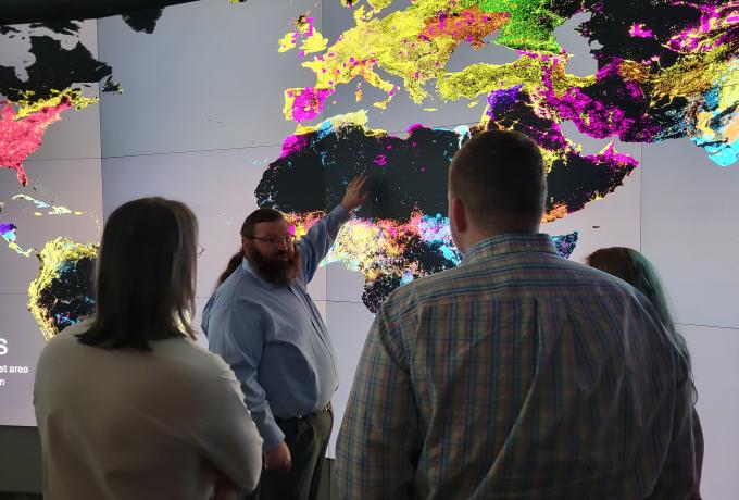 A group of people stand by a colorful map of the world