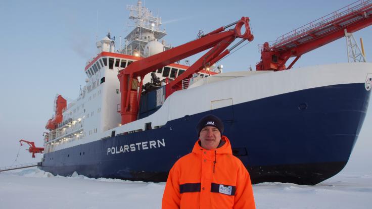 Misha Krassovski, a computer scientist at Oak Ridge National Laboratory, stands in front of the Polarstern, a 400-foot long German icebreaker. Krassovski lived aboard the Polarstern during the first leg of the MOSAiC mission, the largest polar expedition ever. Credit: Misha Krassovski/Oak Ridge National Laboratory, U.S. Dept. of Energy