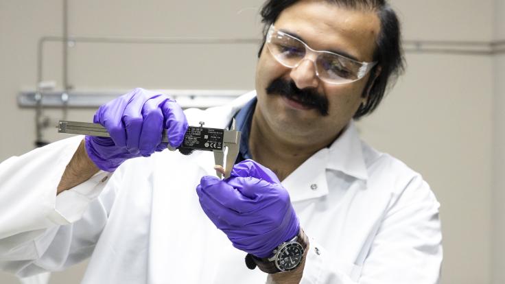 Samarthya Bhagia examines a sample of a thermoplastic composite material additively manufactured using poplar wood and polylactic acid. Credit: Carlos Jones/ORNL, U.S. Dept. of Energy