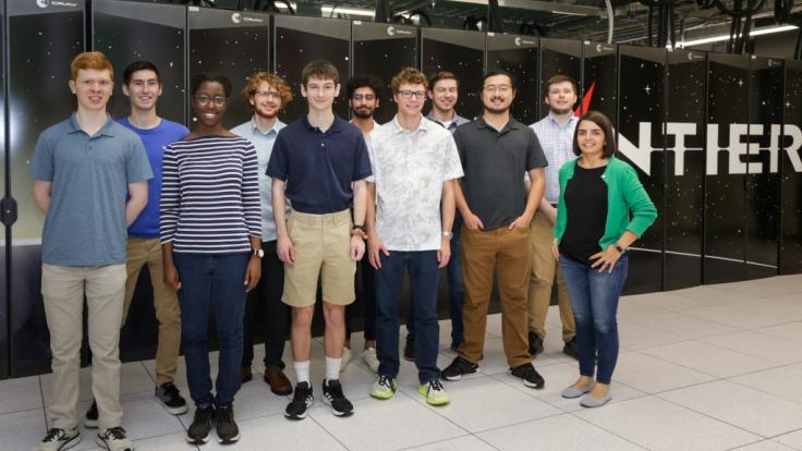 Group of people standing in front of Frontier supercomputer