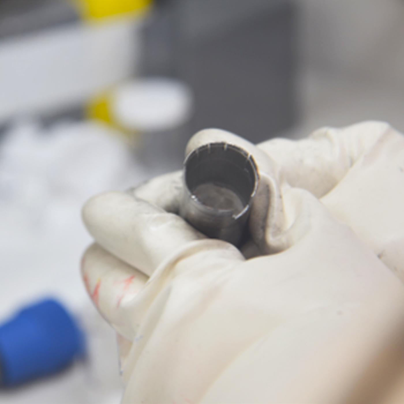 An ORNL researcher holds a capsule of molten salt. Preliminary experiments seem to indicate that irradiation can slow corrosion of metal in liquid salt. Credit: ORNL, U.S. Dept. of Energy