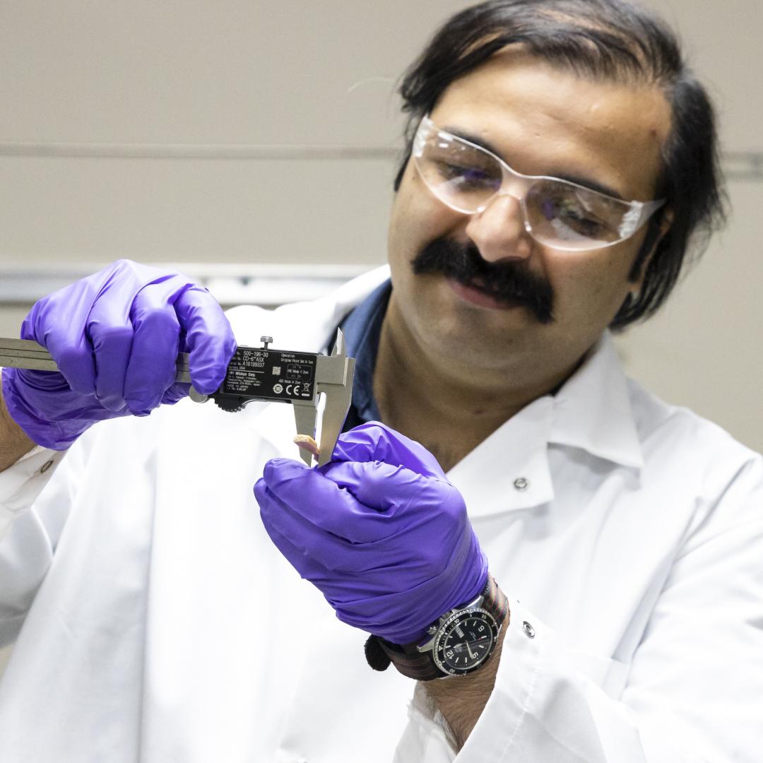 Samarthya Bhagia examines a sample of a thermoplastic composite material additively manufactured using poplar wood and polylactic acid. Credit: Carlos Jones/ORNL, U.S. Dept. of Energy