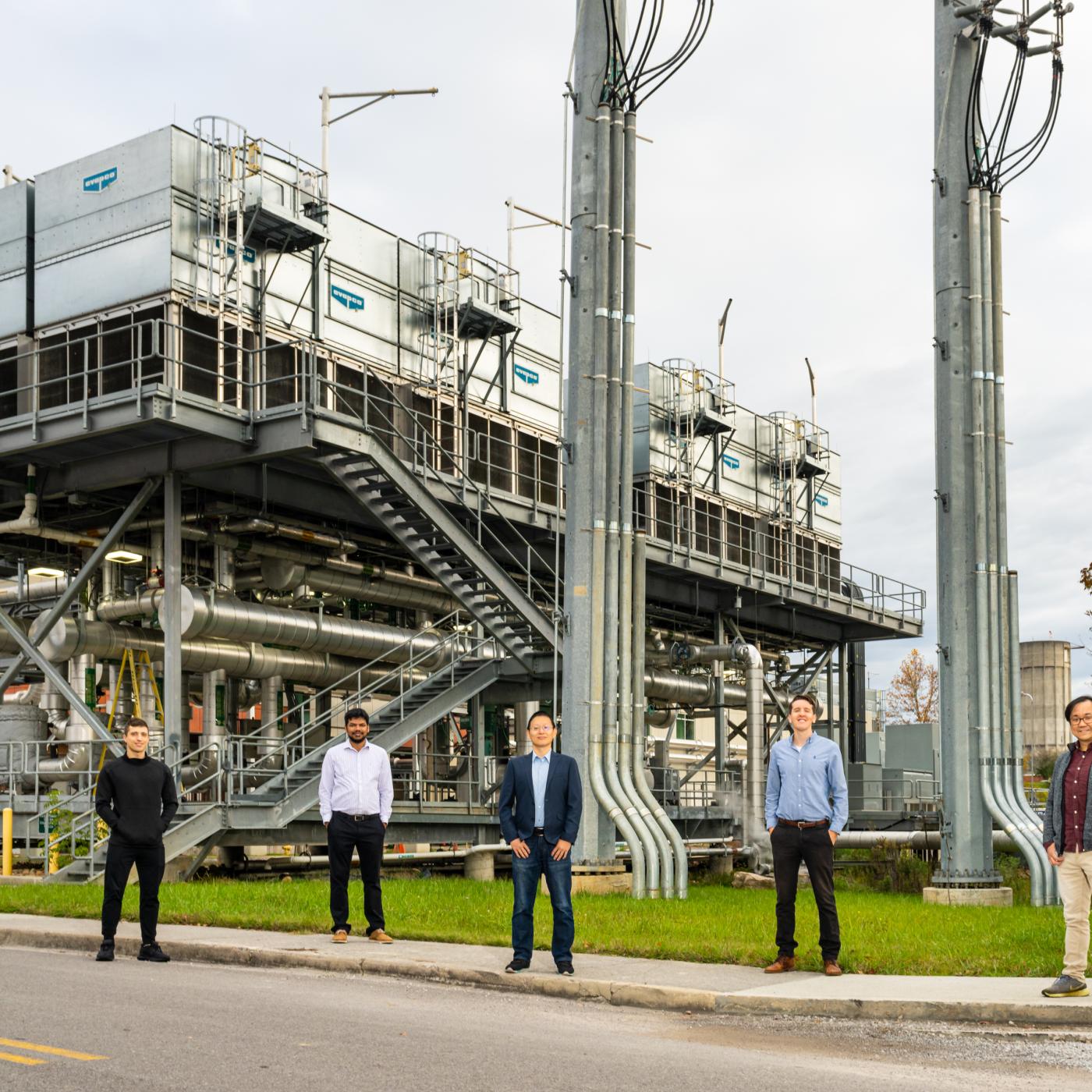 Five men stand in front of Summit's cooling towers