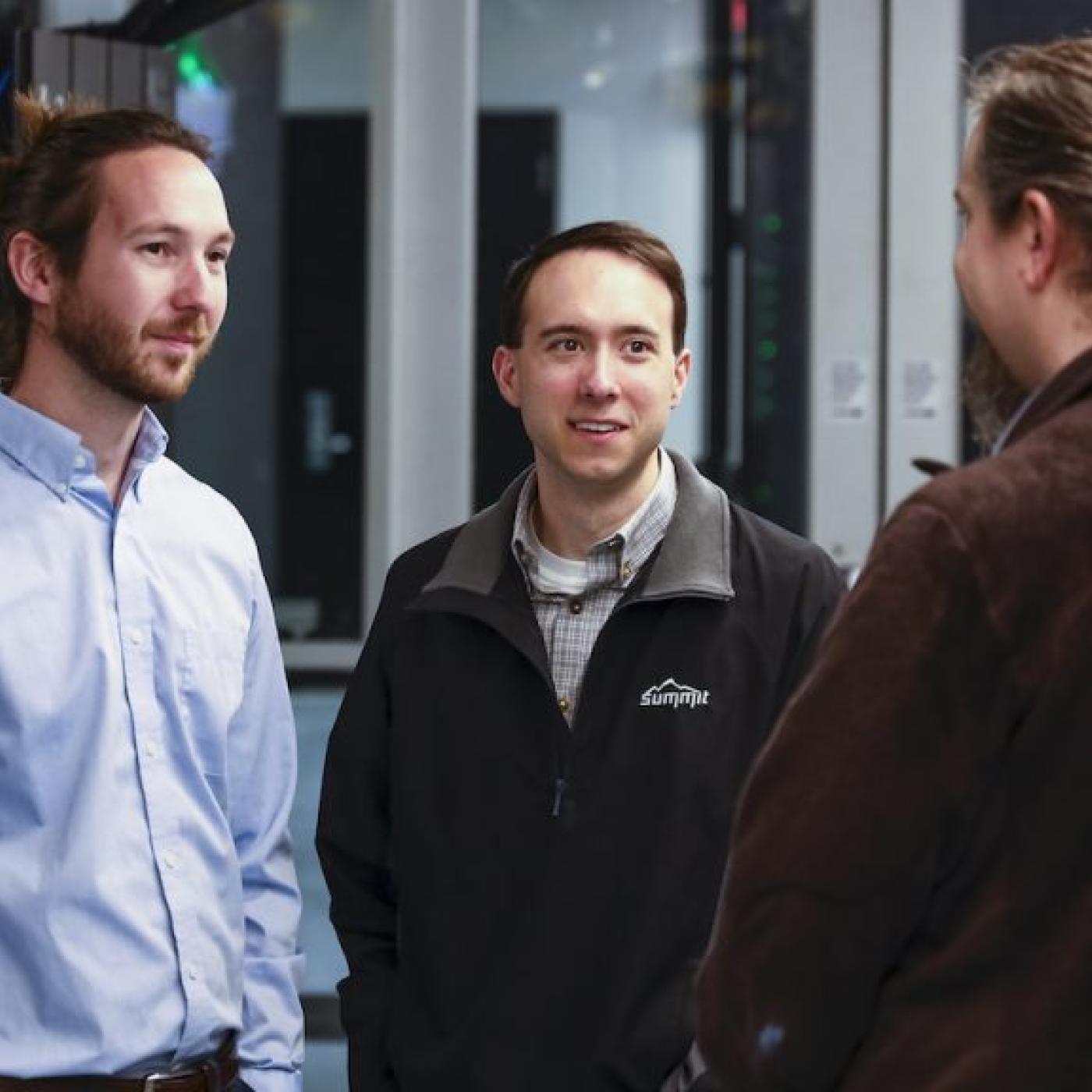 Three men standing together in conversation 