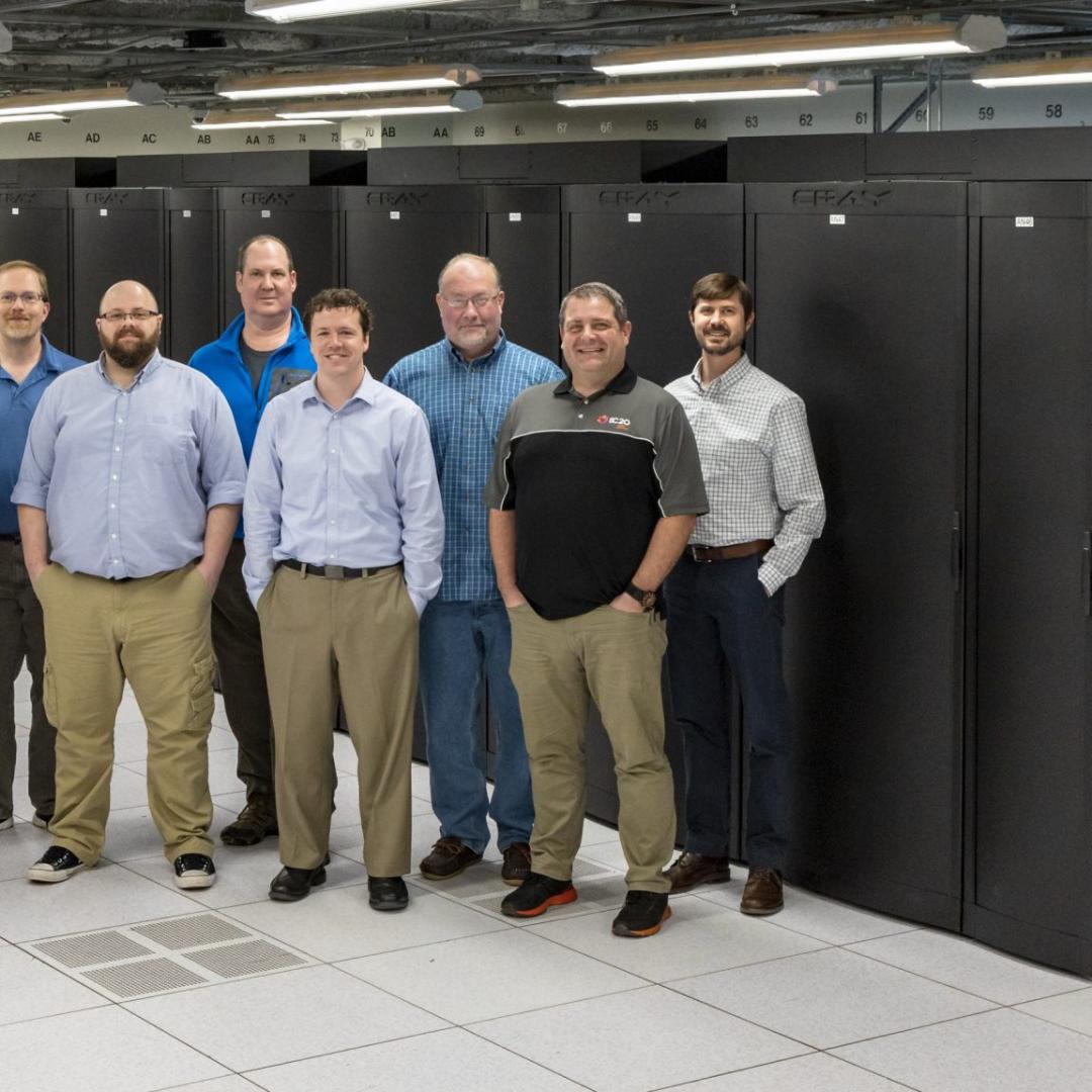 Group of staff standing in front of supercomputer cabinets