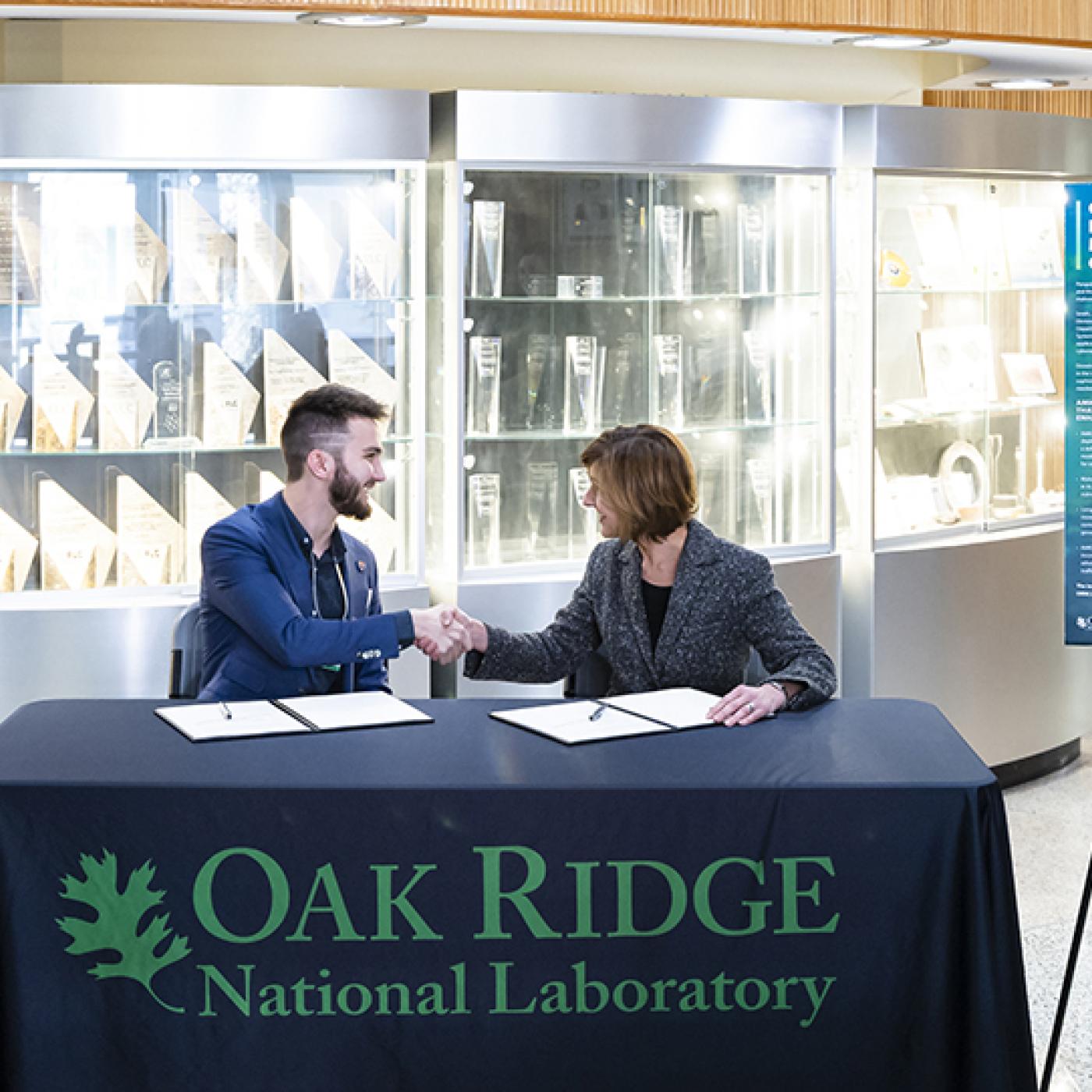 Jared Smith, former ORNL scientist and the inventor of the adversarial malware input generator, or AMIGO, shakes hands with Susan Hubbard, ORNL deputy for science and technology, during an event to celebrate the licensing of AMIGO to Smith's company, Penguin Mustache, on March 21. Credit: Carlos Jones/ORNL, U.S. Dept. of Energy