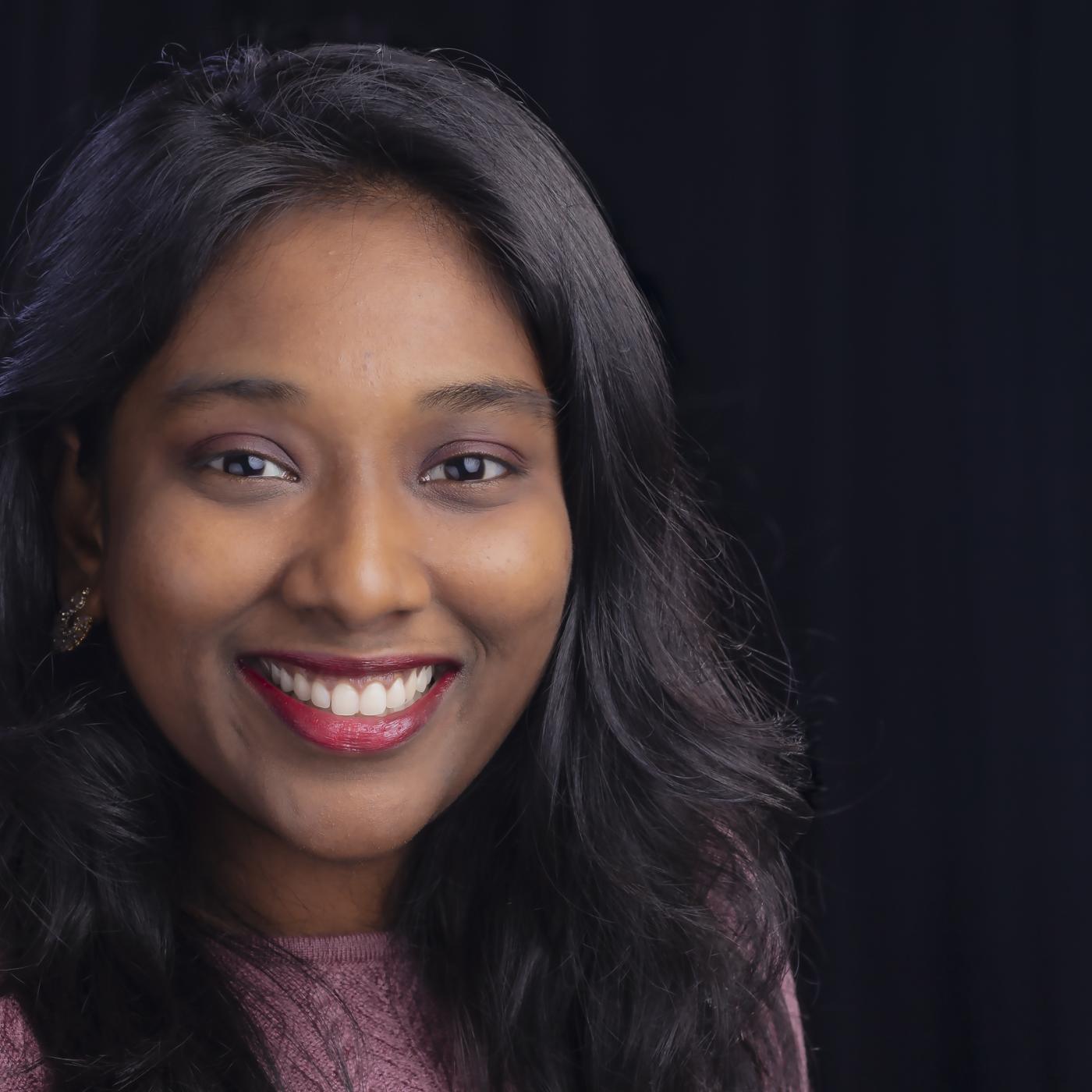 Portrait of Sreelekha Guggilam in purple shirt with black background. 