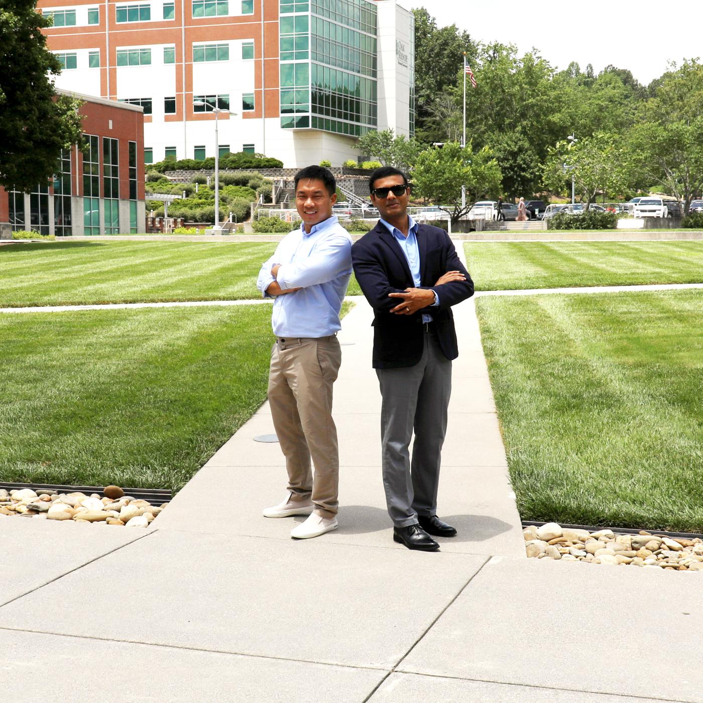 Two researchers standing back to back in a grassy area