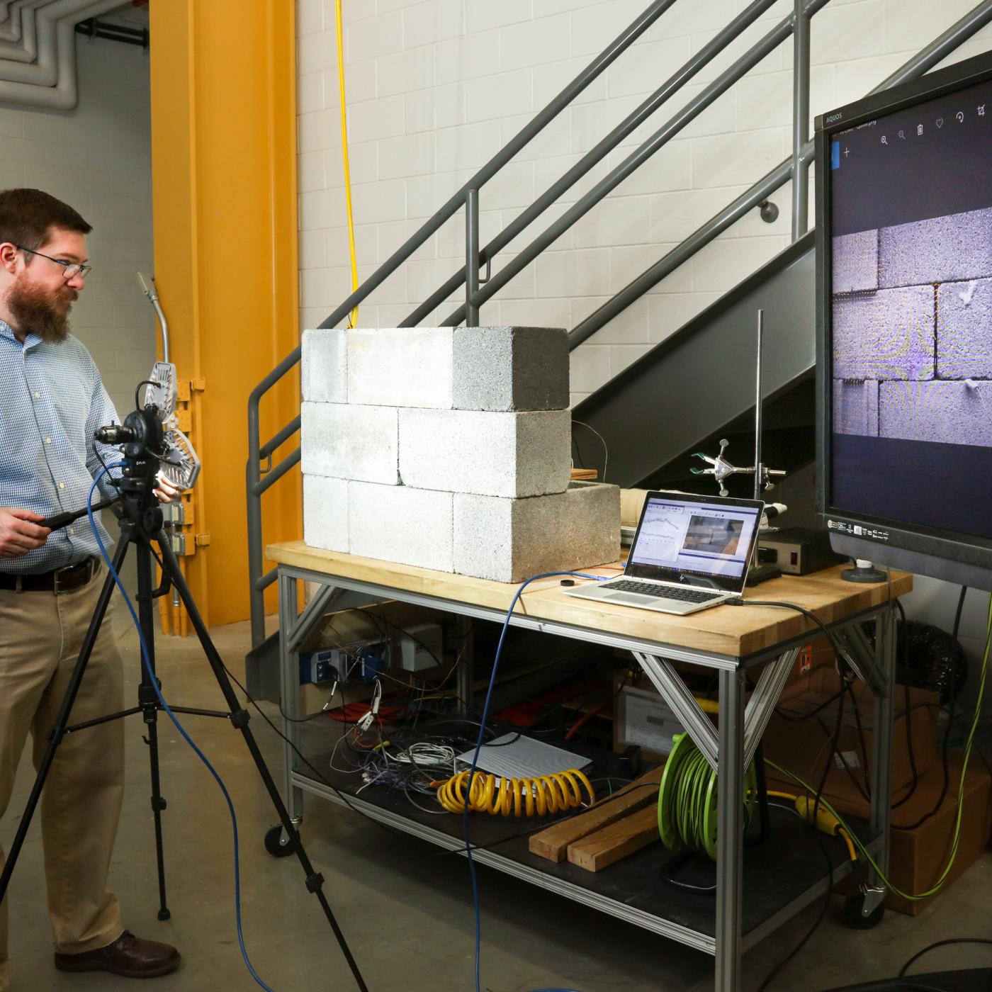 Buildings technologies researcher Philip Boudreaux uses a camera and a technique known as background-oriented schlieren photography to identify air leak sources in a concrete block wall mock-up. Credit: ORNL, U.S. Dept. of Energy