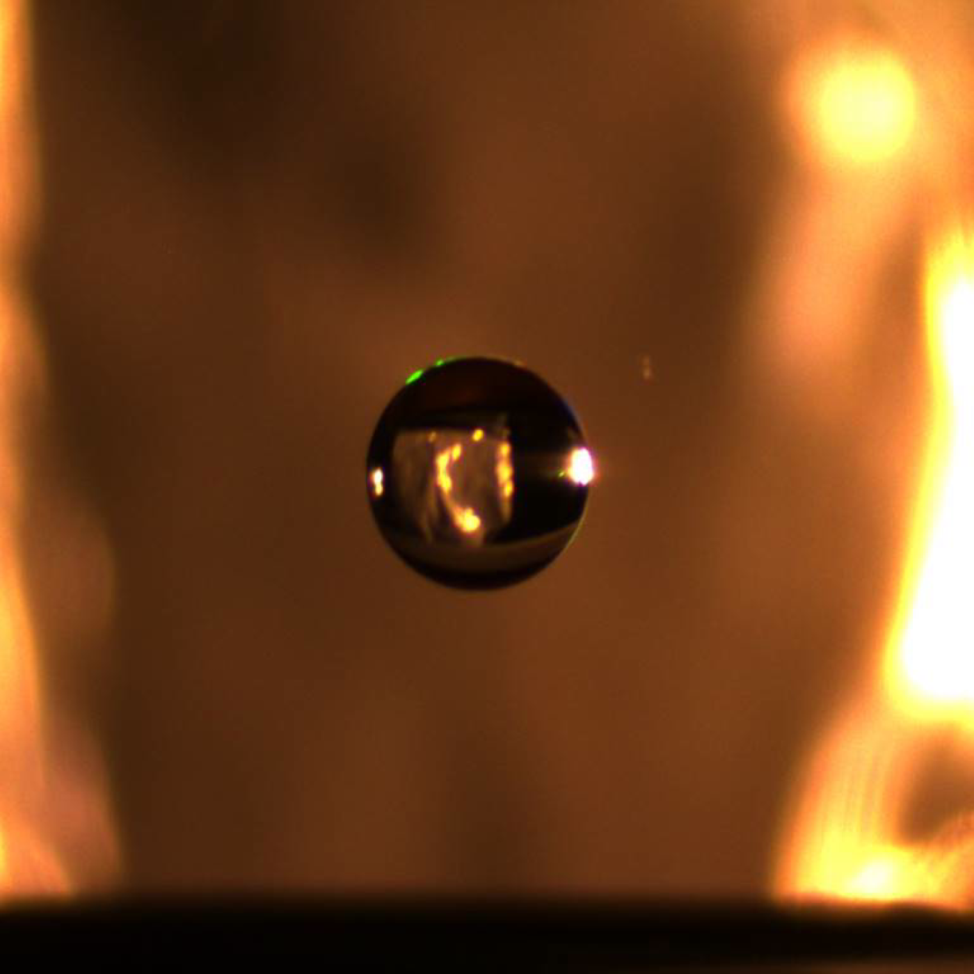 A small droplet of water is suspended in midair via an electrostatic levitator that lifts charged particles using an electric field that counteracts gravity. Credit: Iowa State University/ORNL, U.S. Dept. of Energy