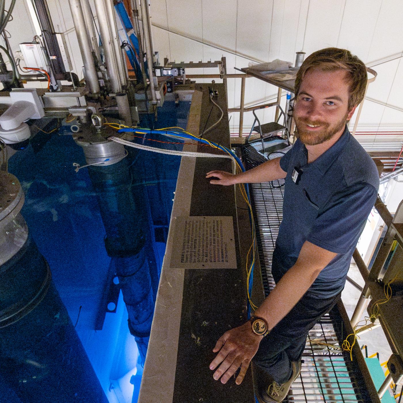 Man in a blue polo is standing over blue water 