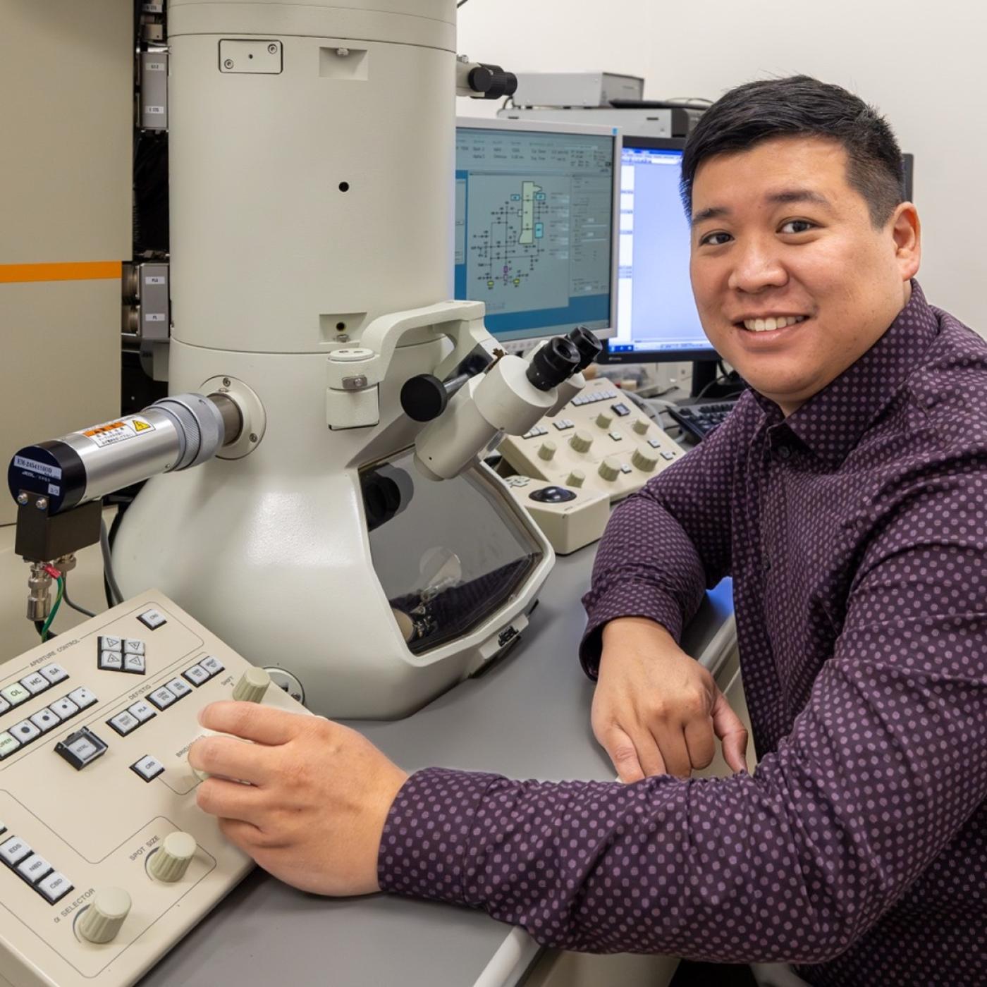 ORNL researcher is sitting at a transmission electron microscopy board in a lab at ORNL 