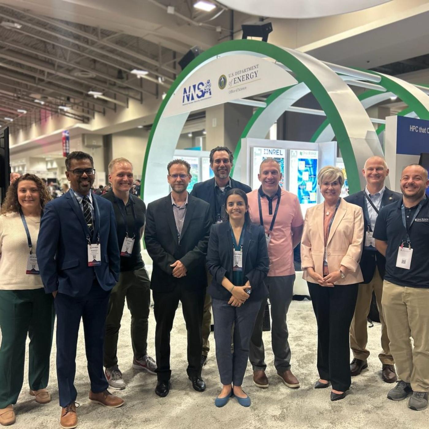 10 staff members are gathering inside the AI expo with a large green and white arch behind them