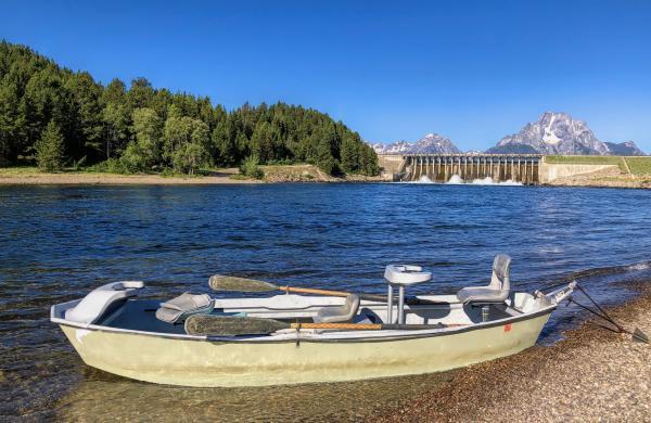 Foreground shows boat, background has hydropower dam