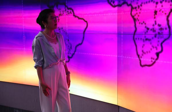 Dan Lu stands in front of a large pink and purple screen 