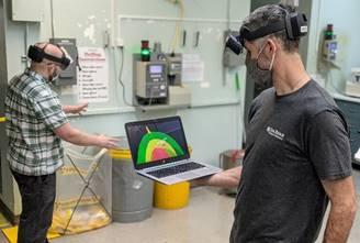 Michael Smith (right) holds a laptop showing what Scott Greenwood (left) sees through augmented reality goggles that are part of the VIPER project funded by ORNL’s Seed program.