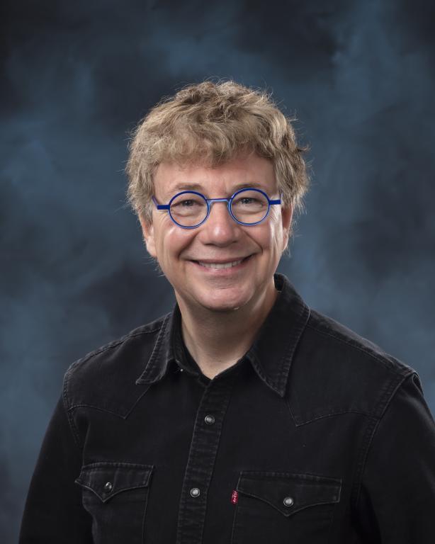 A man wearing a black shirt and blue-framed eyeglasses