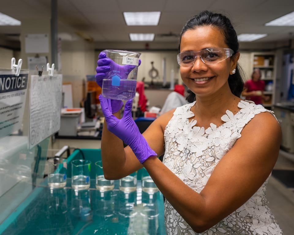 Teresa Mathews holds a beaker in the Aquatic Ecology Lab
