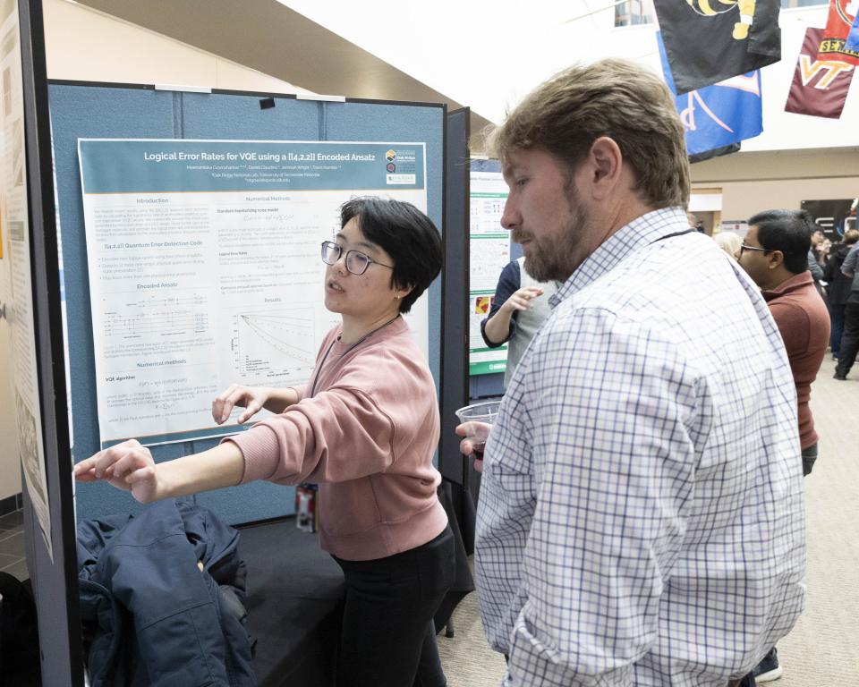 QSC Director Travis Humble, who gave a lunchtime talk on transitioning good ideas to device development, learns about one of the many quantum research efforts featured at the poster session. Credit: Alonda Hines/ORNL, U.S. Dept. of Energy